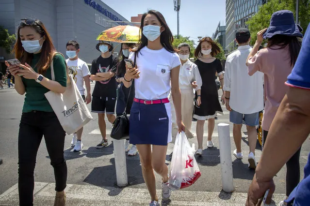 People wear face masks to protect against the coronavirus as they walk across an intersection in Beijing, Friday, June 5, 2020. China on Friday reported five new confirmed coronavirus cases, all of them brought by Chinese citizens from outside the country. (Photo by Mark Schiefelbein/AP Photo)