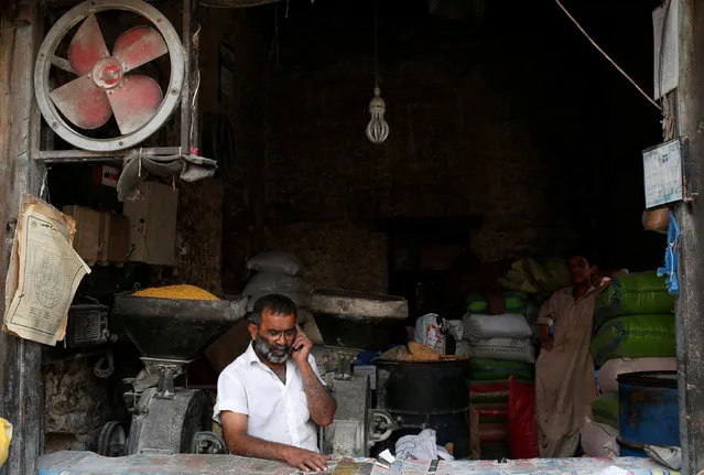 A man talks on a phone near flour mills in a shop during a power breakdown in Karachi, Pakistan May 16, 2018. (Photo by Akhtar Soomro/Reuters)