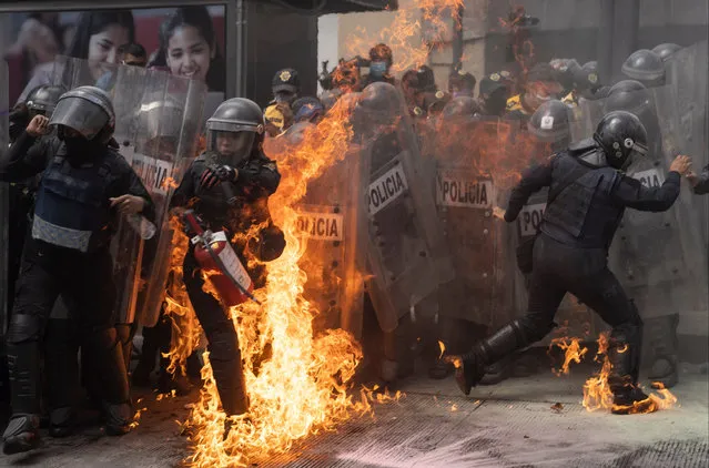 A police officer attempts to put out a fire during a demonstration in favor of the decriminalization of abortion on the International Safe Abortion Day on September 28, 2020 in Mexico City, Mexico. In Mexico, only two states allow legal abortions in women up to twelve weeks of pregnancy. (Photo by Toya Sarno Jordan/Getty Images)