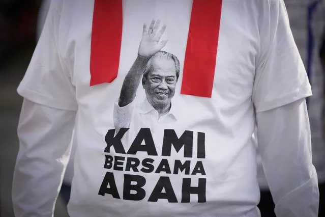 A supporter wears a T-shirt with Malaysia's former Prime Minister Muhyiddin Yassin picture to show support outside courthouse where he appeared on his corruption charges in Kuala Lumpur, Malaysia, Friday, March 10, 2023. Muhyiddin, who led Malaysia from March 2020 until August 2021, will be the country's second leader to be indicted after leaving office. Banner read “we are with you Abah (nick name of Muhyuddin”. (Photo by Vincent Thian/AP Photo)