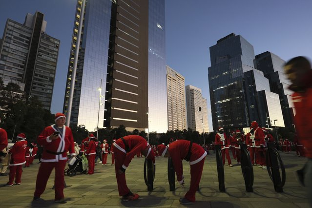 Competitors dressed in Santa Claus suits stretch in preparation for the annual Santa Run, in Mexico City, December 15, 2024. (Photo by Ginnette Riquelme/AP Photo)