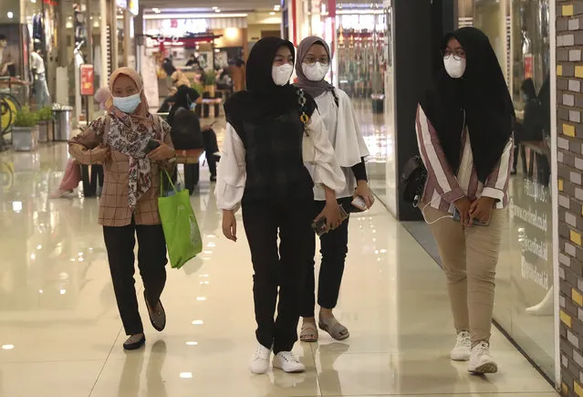 Women wearing face masks as a precaution against coronavirus outbreak walk at a shopping mall in Tangerang, Indonesia, Monday, March 1, 2021. (Photo by Tatan Syuflana/AP Photo)