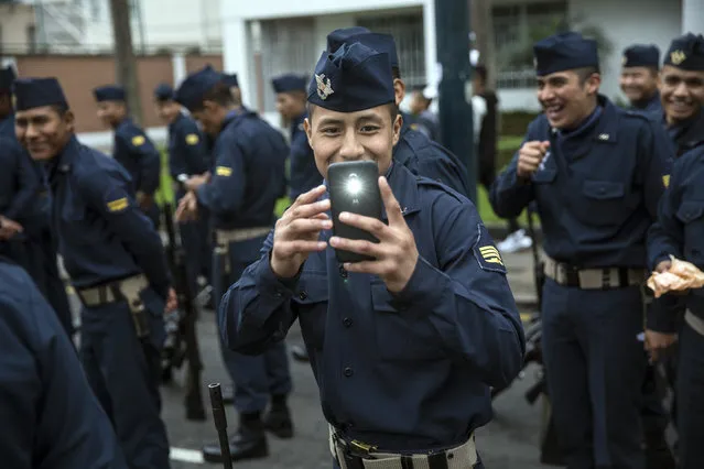In this July 29, 2018 photo, a soldier takes a cell phone picture of journalists before the start of a military parade, part of Independence Day celebrations in Lima, Peru. (Photo by Rodrigo Abd/AP Photo)