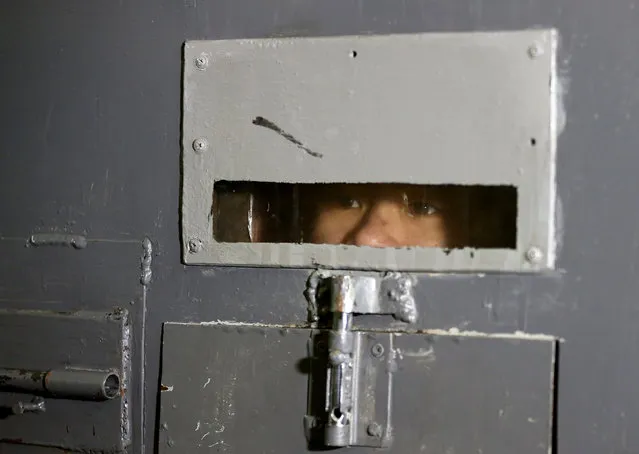 A Vietnamese detained while attempting to cross the border illegally from Belarus to Lithuania, according to border officials, looks through a small window in cell's door at a temporary detention facility in Smorgon, Belarus, November 22, 2016. (Photo by Vasily Fedosenko/Reuters)
