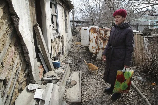A woman visits her home in the separatist-controlled territory to collect her belongings after a recent shelling near a frontline outside Donetsk, eastern Ukraine, Friday, April 9, 2021. Tensions have built up in recent weeks in the area of the separatist conflict in eastern Ukraine, with violations of a cease-fire becoming increasingly frequent. (Photo by AP Photo/Stringer)