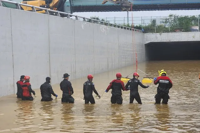 In this photo provided by South Korea National Fire Agency, rescuers search for survivors along a road submerged by floodwaters leading to an underground tunnel in Cheongju, South Korea, Sunday, July 16, 2023. Days of heavy rain triggered flash floods and landslides and destroyed homes, leaving scores of people dead and forcing thousands to evacuate, officials said Sunday. (Photo by South Korea National Fire Agency via AP Photo)