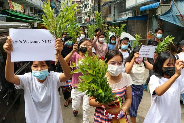Anti-coup protesters hold leaf branches and signs to welcome the NUG, or national unity government as they march Saturday, April 17, 2021 in Yangon, Myanmar.  Opponents of Myanmar’s ruling junta have declared they have formed an interim national unity government with members of Aung San Suu Kyi’s ousted cabinet and major ethnic minority groups. (Photo by AP Photo/Stringer)