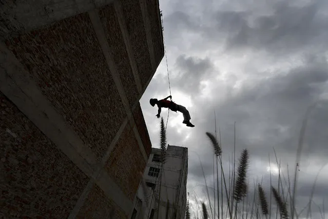 An acrobat of the Third Planet school practices rappel aerial dance from a building in downtown Caracas, Venezuela, Thursday, April 15, 2021. The school offers free aerial dance classes on Tuesdays and Thursdays, amid the new coronavirus pandemic. (Photo by Matias Delacroix/AP Photo)