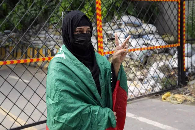 A supporter of Pakistan's former Prime Minister Imran Khan, covers herself with his PTI party flag outside the Zaman park, in Lahore, Pakistan, Saturday, August 5, 2023. Pakistani police on Saturday arrested Khan at his home in the eastern city of Lahore after a court convicted him in an asset concealment case and handed him down a three-year prison sentence. (Photo by K.M. Chaudary/AP Photo)