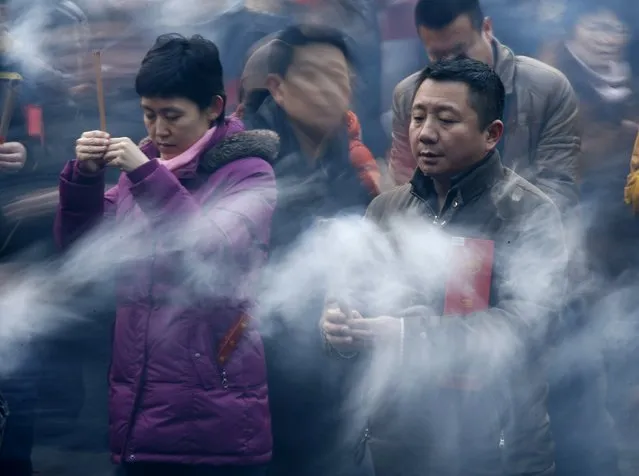 People pray for good fortune as they hold burning incenses on the first day of the Chinese Lunar New Year at Yonghegong Lama Temple, in Beijing, February 19, 2015. (Photo by Kim Kyung-Hoon/Reuters)