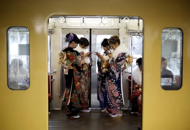 Japanese women wearing kimonos look at their mobile phones after their Coming of Age Day celebration ceremony at an amusement park in Tokyo January 11, 2016. (Photo by Yuya Shino/Reuters)