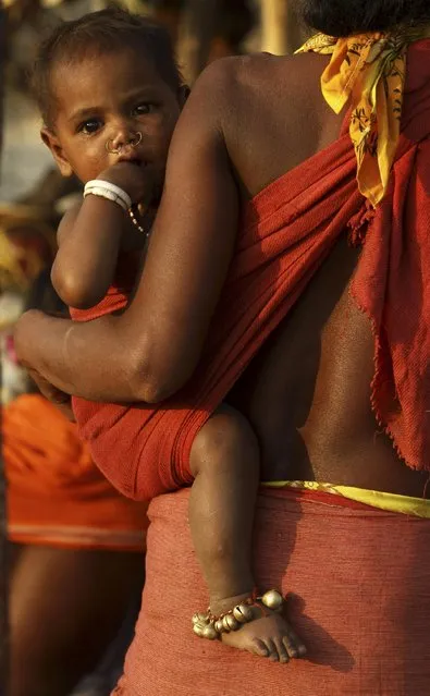 In this Saturday, February 21, 2015 photo, a woman belonging to India’s Dongria tribe carries her child during the two-day long Niyamraja Festival atop the Niyamgiri hills near Lanjigarh in Kalahandi district, Orissa state, India. (Photo by Biswaranjan Rout/AP Photo)