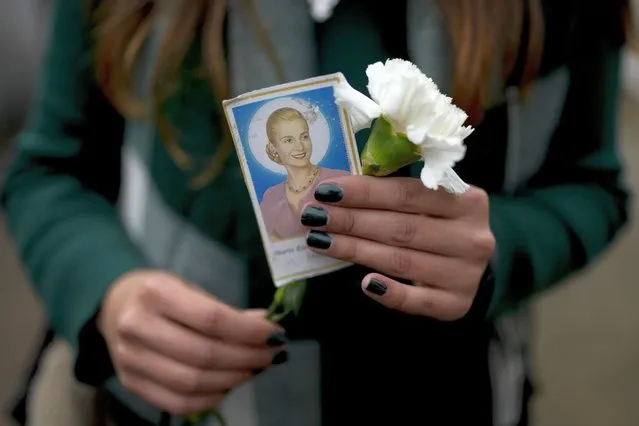 A woman holds a photo of Argentina's late first lady Maria Eva Duarte de Peron, better known as Evita, as she waits her turn to visit Evita's tomb in Buenos Aires, Argentina, Tuesday, July 26, 2022. Argentines commemorate the 70th anniversary of the death of their most famous first lady, who died of cancer on July 26, 1952 at the age of 33. (Photo by Natacha Pisarenko/AP Photo)