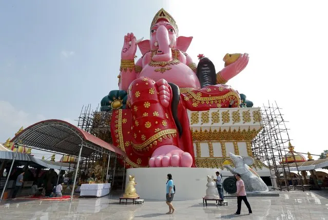 People walk past a giant statue of elephant-headed Hindu god Ganesha at a temple in Chachoengsao province, east of Bangkok, Thailand, January 30, 2016. The statue sits at a height of 49m (161 ft) and measures 19m (62 ft) in width. (Photo by Chaiwat Subprasom/Reuters)