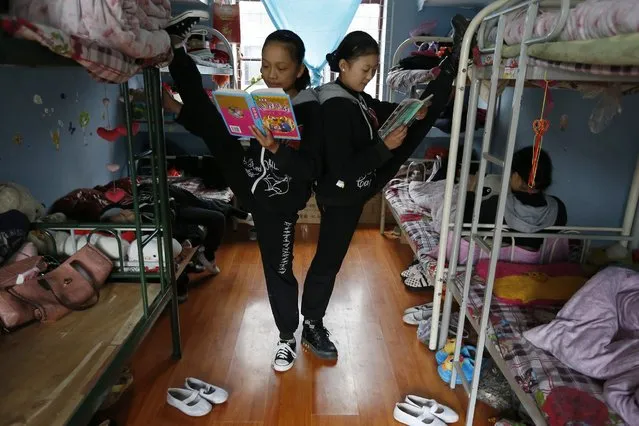 Girls read books as they stretch inside their dormitory at an acrobatics school in Huzhou, Zhejiang province, November 14, 2013. According to a spokesperson from the school, 32 children, whose parents are low-wage migrant workers in the city, are exempted from tuition fees and other costs. The students of the school receive five-hour acrobatic and dance training during the day, and two-hour literacy courses in the evening. (Photo by Reuters/Stringer)