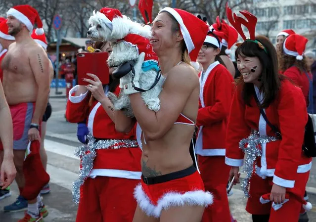 People take part in a half naked Santa run in downtown Budapest, Hungary, December 9, 2018. The partakers danced, ran, walked and laughed on the streets of Budapest, while others opted to simply raise money for the chosen charity. Many people had the names of their charities written on their bellies, while others were dressed in full Santa outfits. (Photo by Bernadett Szabo/Reuters)