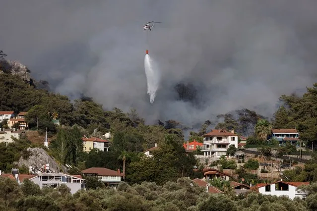 A helicopter waterbombs a wildfire burning at a rural area of Marmaris district of Mugla, Turkey, 31 July 2021. (Photo by Erdem Sahin/EPA/EFE)
