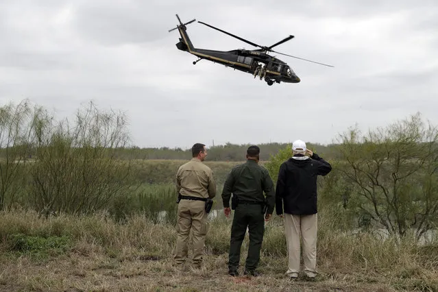 President Donald Trump salutes as a U.S. customs and Border Protection helicopter passes as he tours the U.S. border with Mexico at the Rio Grande on the southern border, Thursday, January 10, 2019, in McAllen, Texas. (Photo by Evan Vucci/AP Photo)