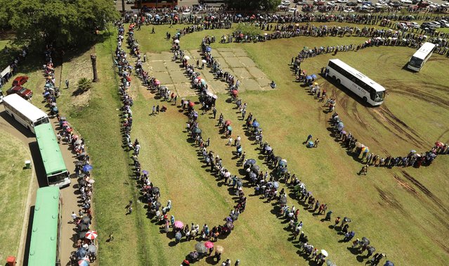 People stand in a long, winding line to catch a bus to see the remains of Nelson Mandela at the Union Buildings in Pretoria, South Africa on Thursday, December 12, 2013. (Photo by Themba Hadebe/AP Photo)