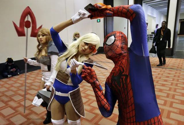 Linda Thach, center, of Lowell, Mass., in character as Vegeta from the Japanese animated series Dragon Ball Z, and Peter Van, also of Lowell, as Spiderman, right, do the fusion dance from Dragon Ball Z, while attending the annual three-day Japanese animation convention, Sunday, April 5, 2015, in Boston. (Photo by Steven Senne/AP Photo)
