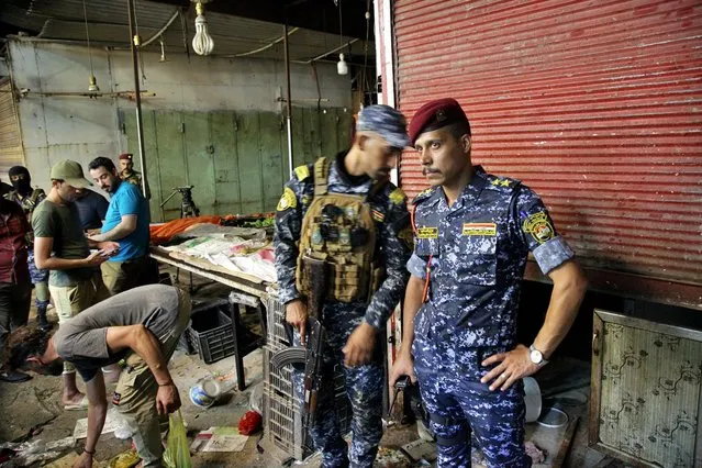 People and security forces gather at the site of a bombing in Wahailat market in Sadr City, Iraq, Monday, July 19, 2021. A roadside bomb attack targeted a Baghdad suburb Monday, killing at least 18 people and wounding dozens of others at a crowded market, Iraqi security officials said. (Photo by Khalid Mohammed/AP Photo)