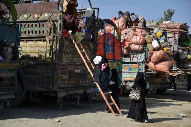 Afghan refugees climb a ladder onto a vehicle after arriving from Pakistan at a registration centre near the Afghanistan-Pakistan border in Spin Boldak district of Kandahar province on November 28, 2023. Border officials say at least 210,000 Afghans, including many who have lived decades, if not their whole lives, outside their country, have passed through the Torkham border point since Pakistan ordered those without documents to leave. (Photo by Sanaullah Seiam/AFP Photo)