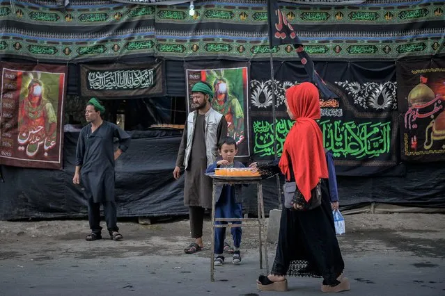 Shiite Muslims distribute sherbet during the Ashura procession which is held to mark the death of Imam Hussein, the grandson of Prophet Mohammad, along a road in Kabul on August 19, 2021, amid the Taliban's military takeover of Afghanistan. (Photo by Hoshang Hashimi/AFP Photo)