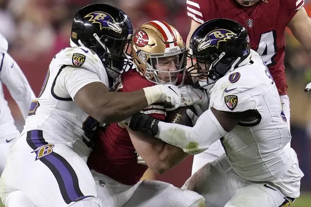 San Francisco 49ers running back Christian McCaffrey, middle, is tackled by Baltimore Ravens defensive tackle Justin Madubuike, left, and linebacker Roquan Smith (0) during the second half of an NFL football game in Santa Clara, Calif., Monday, December 25, 2023. (Photo by Godofredo A. Vásquez/AP Photo)