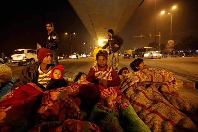 A family gather under blankets to shelter from the cold beneath a flyover in Delhi, India January 16, 2017. (Photo by Cathal McNaughton/Reuters)