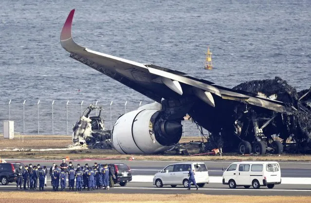 Police investigators gather beside  the burn-out wreckage of Japan Airlines plane at Haneda airport on Thursday, January 4, 2024, in Tokyo, Japan. A transcript of communication between traffic control and two aircraft that collided and burst into flames at Tokyo’s Haneda Airport showed that only the larger Japan Airlines passenger flight was given permission to use the runway where a coast guard plane was preparing for takeoff. (Photo by Kyodo News via AP Photo)