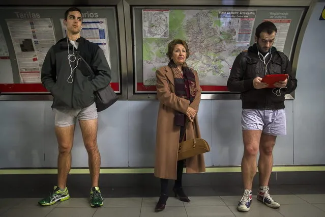A passenger stands in between participants as they wait for the train without their pants during the 5th annual “No Pants Subway Ride” in Madrid, Spain, Sunday, January 12, 2014. (Photo by Andres Kudacki/AP Photo)