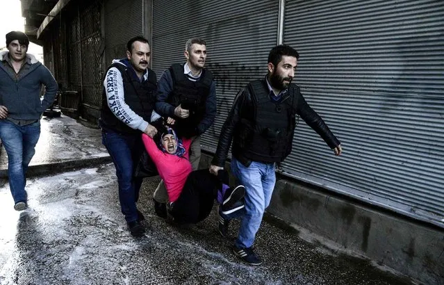 Turkish plain clothes police officers detain a woman during clashes between Turkish forces and Kurdish people in the centre of Diyarbakir, during a protest against the curfew in the Sur district of Diyarbakir, on March 2, 2016. Ankara has repeatedly imposed curfews for military operations in southeastern urban centres, in a measure the government says is necessary to root out PKK militants who were taking de-facto control in some areas. The Cizre curfew was one of the longest but a lockdown has also been in place since December 2 in the central Sur district which is home Turkey's biggest Kurdish majority city, Diyarbakir. (Photo by Ilyas Akengin/AFP Photo)