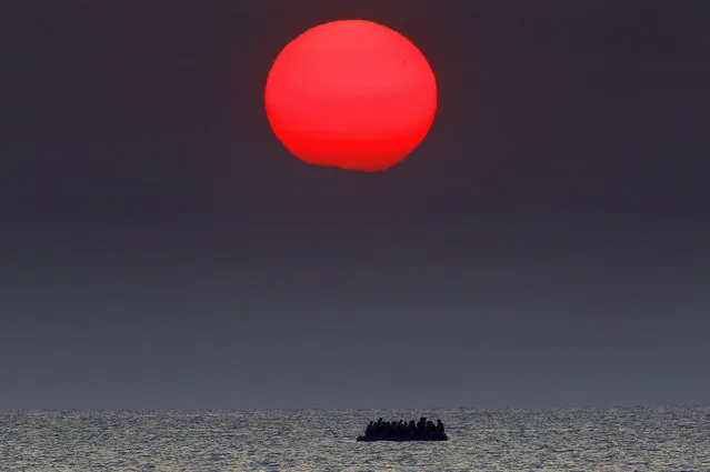 A red sun is seen over a dinghy overcrowded with Syrian refugees drifting in the Aegean sea between Turkey and Greece after its motor broke down off the Greek island of Kos, August 11, 2015. (Photo by Yannis Behrakis/Reuters)