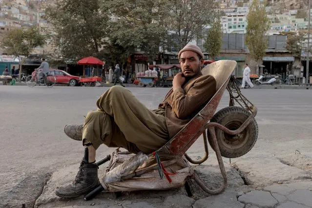 A worker with a with a prosthetic leg sits in a wheelbarrow in Kabul, Afghanistan, October 4, 2021.. (Photo by Jorge Silva/Reuters)