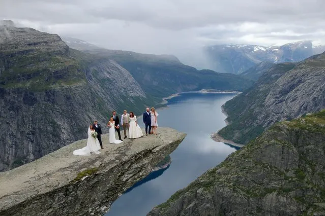 (From L) Bridal couples Lise Sydnes Boerdal and Njal-Stian Boerdal, Ina Kulsveen and Kjetil SkjÊrbÊk, Katarina Karlsson and Fredrik Gustavsson, and Tinna Bundgaard Frentz and Kasper Soerensen pose after their wedding ceremony on Trolltunga ('Troll tongue') rock formation in Ullensvang Municipality, Vestland county, Norway on August 14, 2021. The cliff of Trolltunga, popular with hikers and tourists, juts horizontally out from the mountain about 700 metres above lake Ringedalsvatnet. (Photo by Ase Marie Evjen/Trolltunga AS/NTB via AFP Photo)
