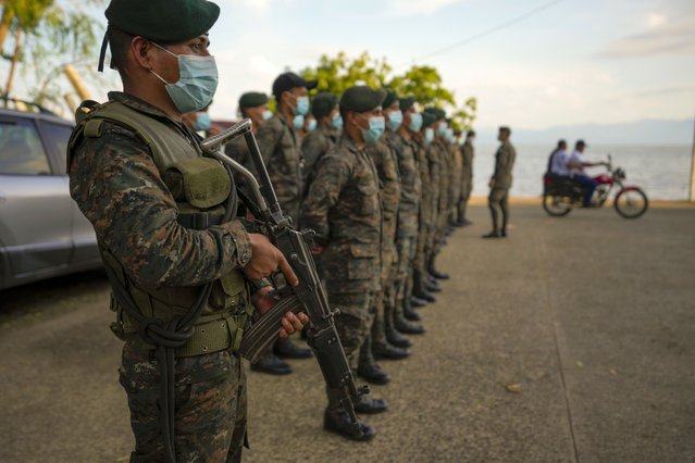 Soldiers receive instructions in El Estor, at the northern coastal province of Izabal, Guatemala, Sunday, October 24, 2021. The Guatemalan government declared a month-long, dawn-to-dusk curfew and banned pubic gatherings following two days of protests against a mining project. (Photo by Moises Castillo/AP Photo)