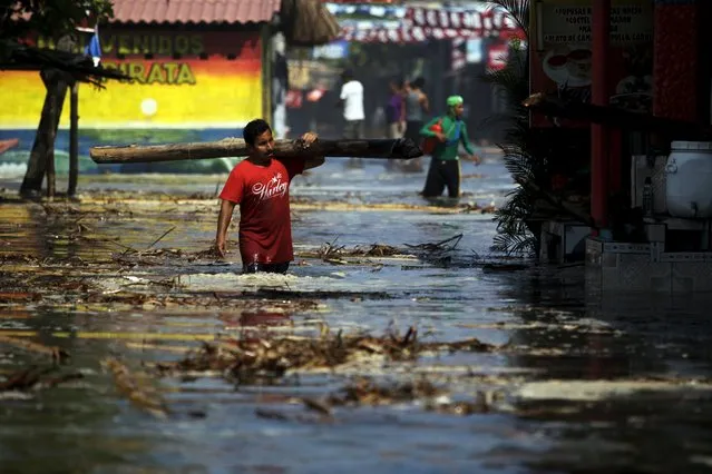 A man walks on a flooded street after waves broke in from El Majahual beach in La Libertad May 3, 2015. (Photo by Jose Cabezas/Reuters)