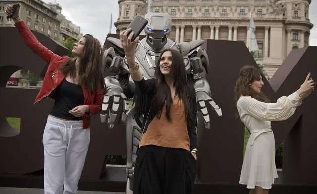 People take “selfies” with Titan the Robot, in Bucharest, Romania, Monday, May 11, 2015. Titan the robot is produced by British company Cyberstein Robots Ltd and gained world recognition in pop videos dancing alongside artists such as Rihanna in music videos. (Photo by Vadim Ghirda/AP Photo)