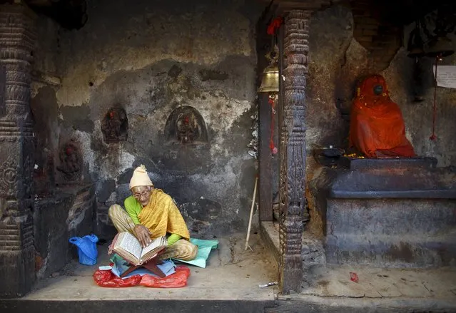 A woman offers prayers by reading a holy book as she sits in the remains of a temple after the earthquake in Kathmandu May 14, 2015. (Photo by Navesh Chitrakar/Reuters)