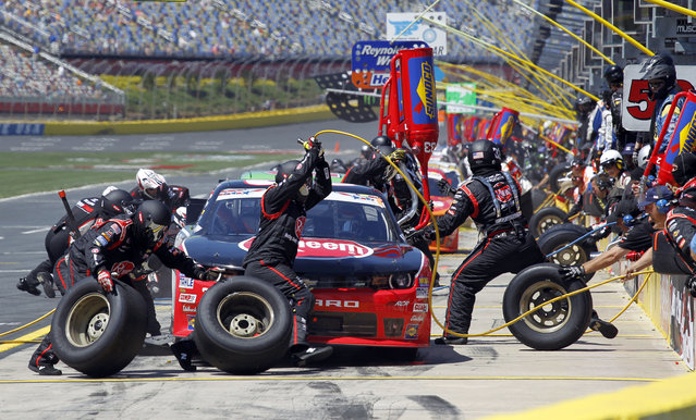 Crew members work during a pit stop for driver Austin Dillon's car during the NASCAR Xfinity series auto race at Charlotte Motor Speedway in Concord, N.C., Saturday, May 23, 2015. (Photo by Terry Renna/AP Photo)