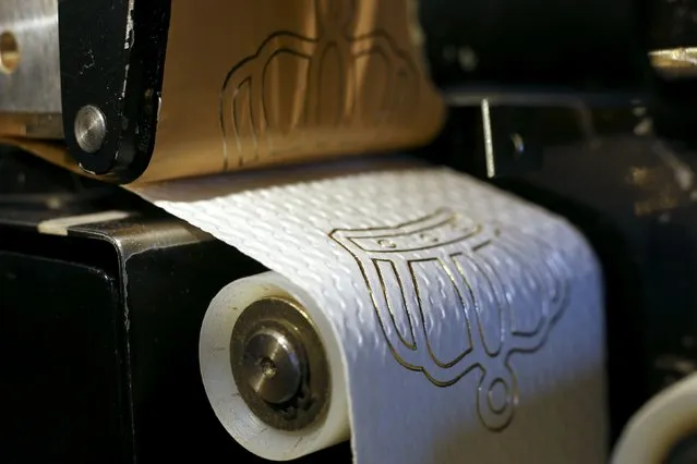 Luxury toilet paper with a 24 carat gold motifs is produced at the Tissue Design workshop of Fritz Loibl in Grafenau March 31, 2014. Each gold embossed toilet roll, which is handcrafted by owner Fritz Loibl with customised designs, costs 179 Euros (246 $) and are sold worldwide. (Photo by Michael Dalder/Reuters)