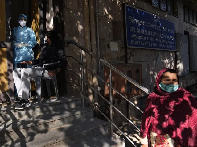 A woman waits for her Covid 19 antigen test result as other waits to get tested at a health center, in New Delhi, India, Friday, January 28, 2022. Indian health officials said that the first signs of COVID-19 infections plateauing in some parts of the vast country were being seen, but cautioned that cases were still surging in some states. (Photo by Manish Swarup/AP Photo)