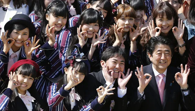 Japan's Prime Minister Shinzo Abe (front row, R) poses with entertainment celebrities including members of the girls' pop group HKT48, led by Rino Sashihara (middle row, 3rd L), at a cherry blossom viewing party at Tokyo's Shinjuku Gyoen park April 12, 2014. Thousands of people including entertainers, athletes and politicians were invited to the annual party hosted by Abe. (Photo by Issei Kato/Reuters)