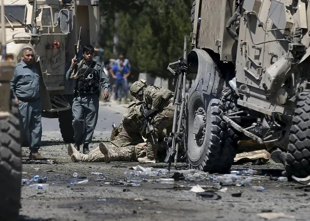 U.S. soldiers attend to a wounded soldier at the site of a blast in Kabul, Afghanistan June 30, 2015. A suicide bomber attacked a convoy of foreign troops serving with NATO on the main road running between Kabul's airport and the U.S. embassy, police and security officials said. (Photo by Mohammad Ismail/Reuters)