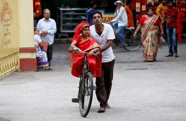 A man carries his daughter, dressed as Kumari, on a bicycle, as they arrive to attend rituals to celebrate the Navratri Festival, inside the Adyapeath Temple, on the outskirts of Kolkata, April 5, 2017. (Photo by Rupak De Chowdhuri/Reuters)