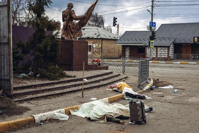 The dead bodies of people killed by Russian shelling lie covered in the street in the town of Irpin, Ukraine, Sunday, March 6, 2022. (Photo by Diego Herrera Carcedo/AP Photo)