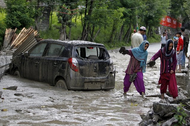 Kashmiri villagers walk next to a damaged car through the cloud burst hit area of Kullan village in Ganderbal district, July 17, 2015. At least four people were killed in a series of cloud bursts that were reported from several parts of Kashmir during heavy rainfall, local media reported on Friday. (Photo by Danish Ismail/Reuters)