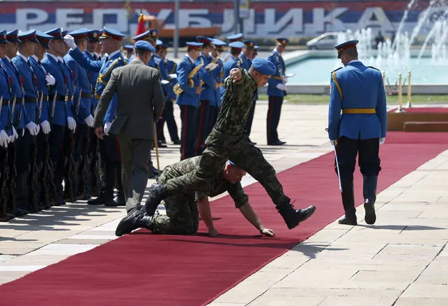 Serbian army soldiers prepare the red carpet before the welcoming ceremony for Bosnia's three-member presidency in Belgrade, Serbia, Wednesday, July 22, 2015. Bosnia's three-member presidency visits Belgrade following recent tensions over the 20th anniversary of the Srebrenica massacre of Muslims by Serbs. (Photo by Darko Vojinovic/AP Photo)