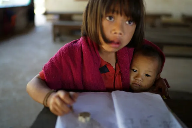 A hill tribe student holds her younger brother during a class at the Ban Mae Chan Tha Border Patrol Police School, at Umphang district, in Tak province, Thailand, February 6, 2017. (Photo by Athit Perawongmetha/Reuters)