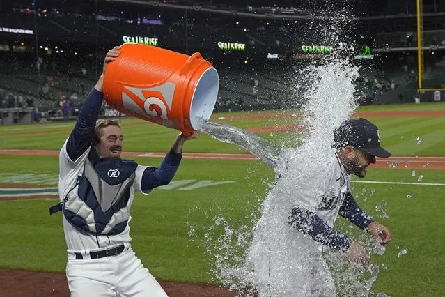 Seattle Mariners' Eugenio Suarez is doused with ice water by catcher Tom Murphy, left, during an interview after the Mariners defeated the Texas Rangers 6-2 in a baseball game Tuesday, April 19, 2022, in Seattle. (Photo by Ted S. Warren/AP Photo)